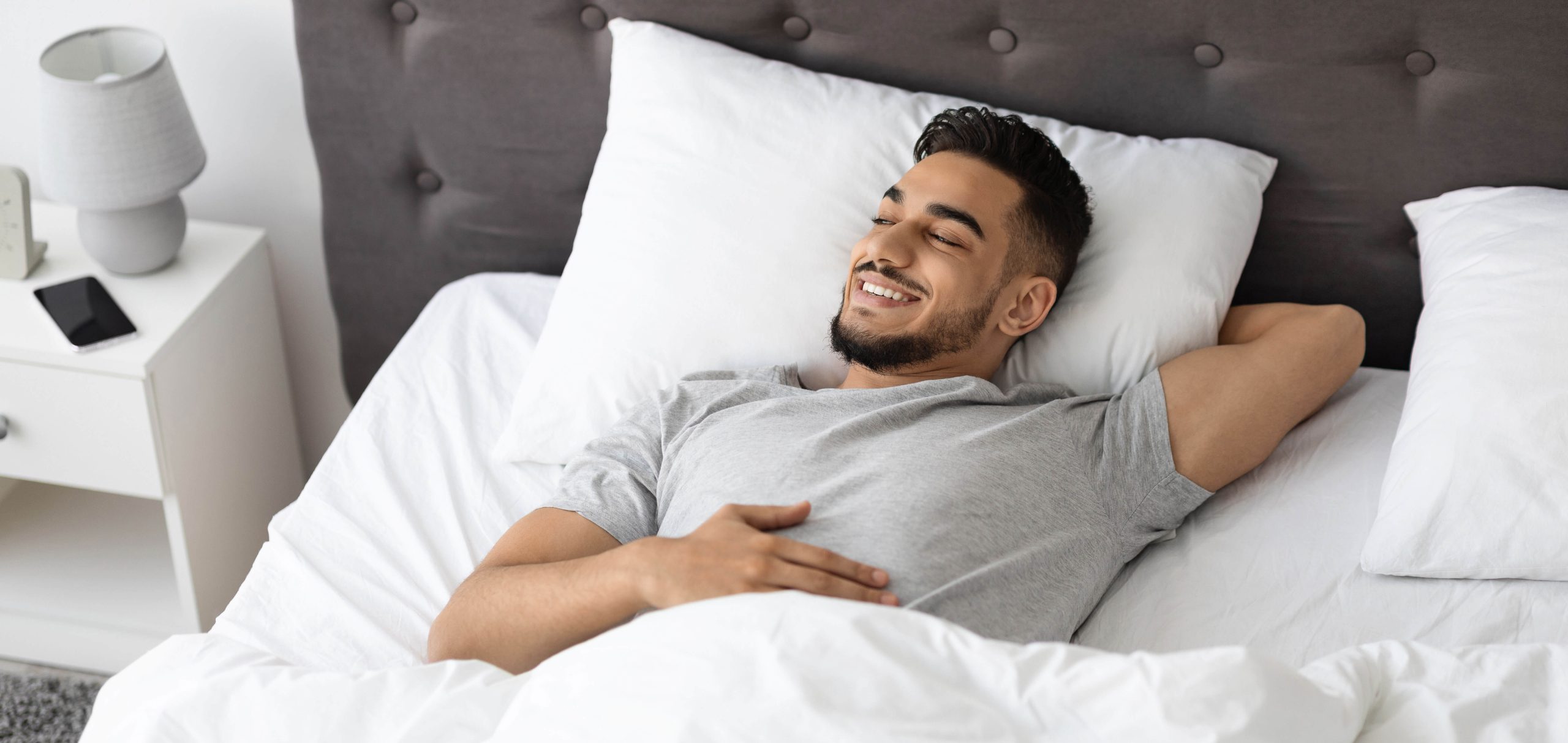 Portrait of happy middle eastern man relaxing in bed